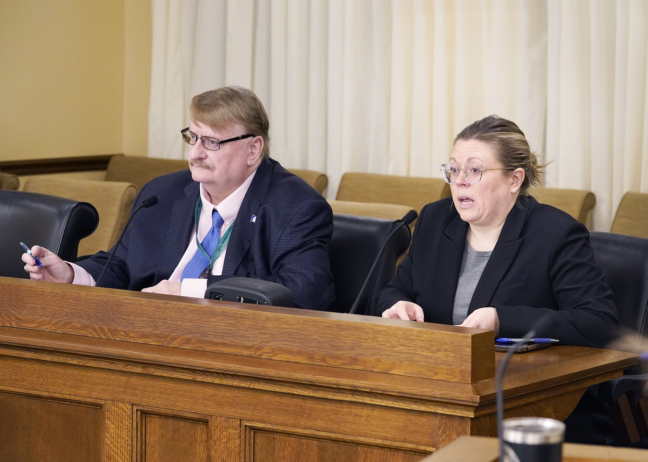 Nicole Freeman, government relations director for the Office of the Secretary of State, testifies March 9 on a bill sponsored by Rep. Duane Quam, left, that would require certain voters to cast provisional ballots. (Photo by Andrew VonBank)